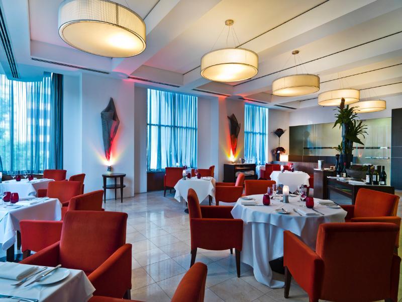 Amora Hotel Jamison Σίδνεϊ Εξωτερικό φωτογραφία The photo shows an elegant restaurant interior. The space features stylish red chairs arranged around white tablecloth-covered tables. There are decorative elements like sculptures or artworks on the walls, and large windows covered with sheer curtai